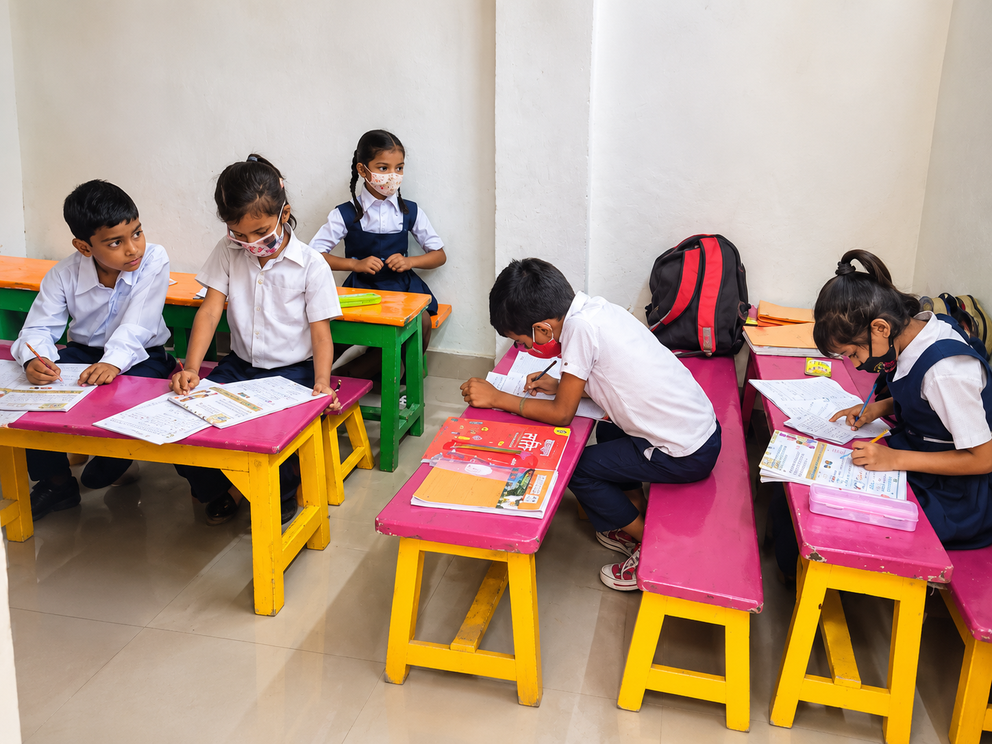 masked children studying in colorful classroom